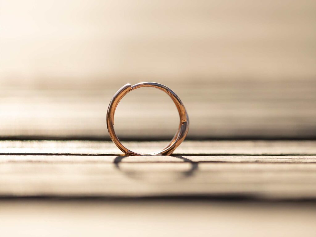 Anillo minimalista dorado sobre fondo textil beige.