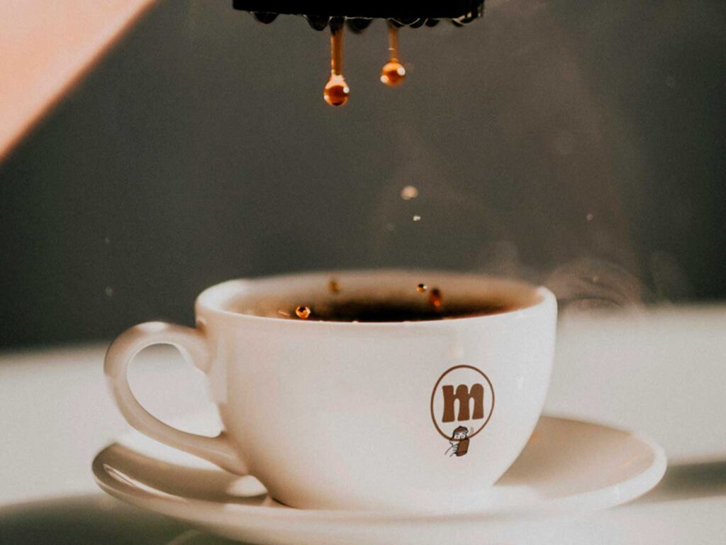 Taza blanca con diseño impreso del logotipo en marrón, ejemplo de aplicación de identidad visual sobre soporte cerámico.