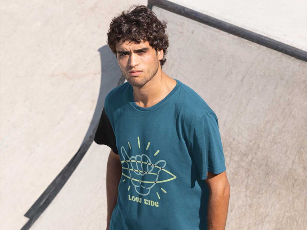 Diseño de camiseta azul con gráfico surfista y estética veraniega, ejemplo de identidad visual aplicada a moda y branding juvenil.