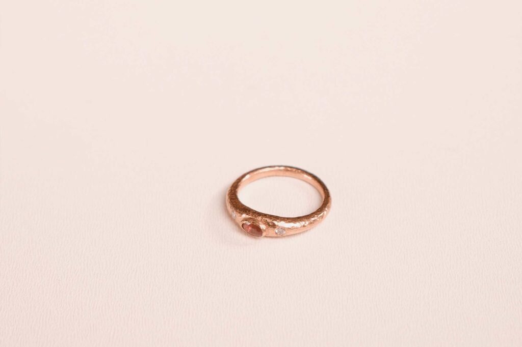 Anillo artesanal con textura orgánica sobre fondo neutro.