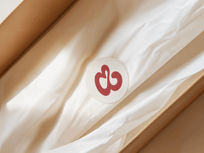 Packaging artesanal con logotipo impreso en rojo para marca de joyería.