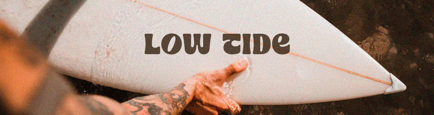 Tabla de surf con el logotipo Low Tide, diseño de marca para empresa relacionada con el surf y estilo de vida costero.